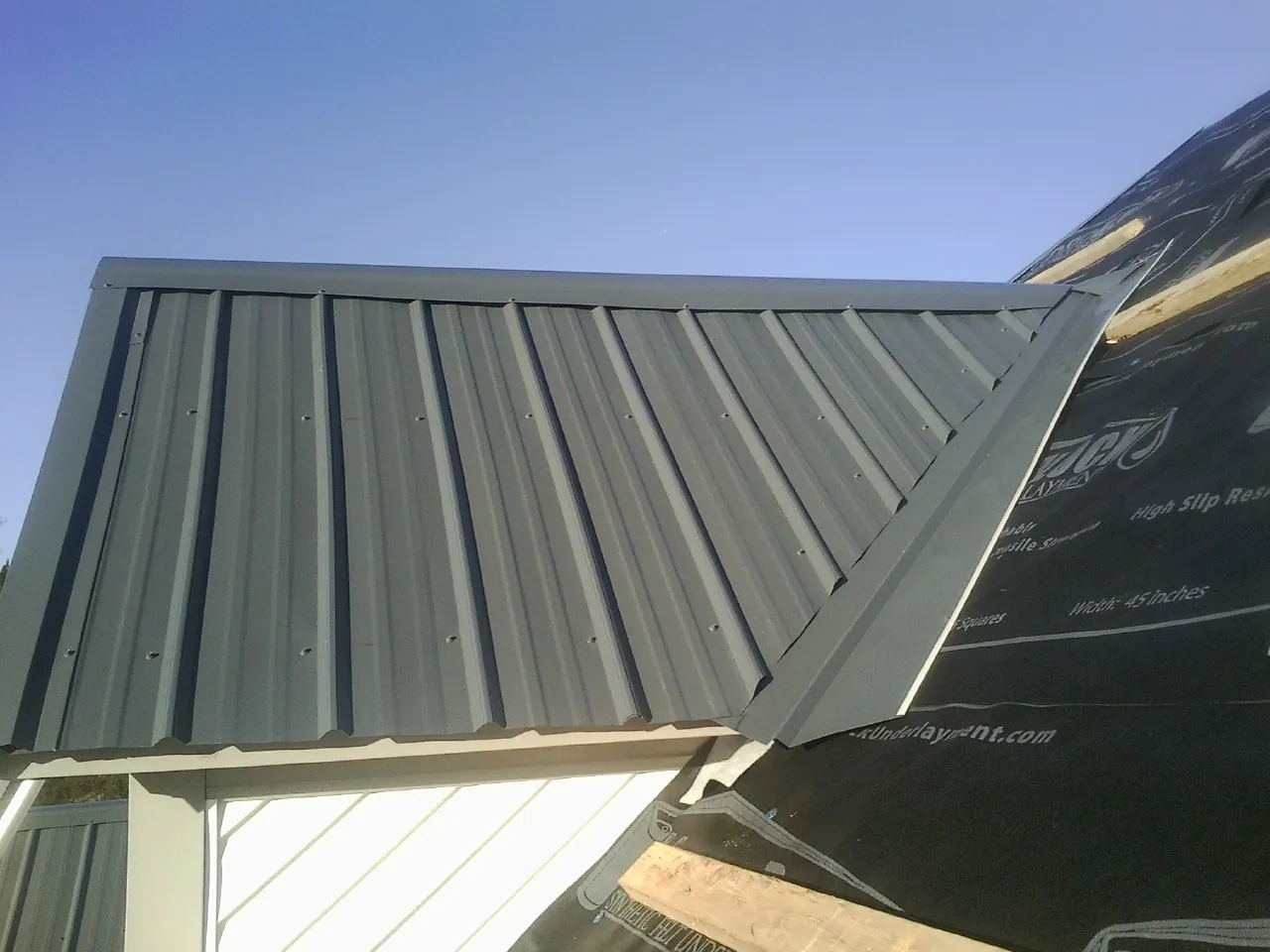 Gray metal roof panels going on over a garage gable in Mineral Wells