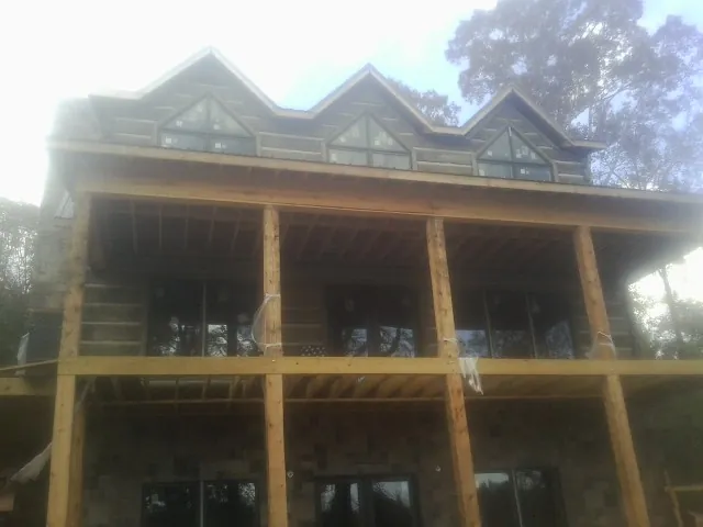 Dormers and porch framing on a large log home under construction — Roof Coating work by our crew in Mineral Wells