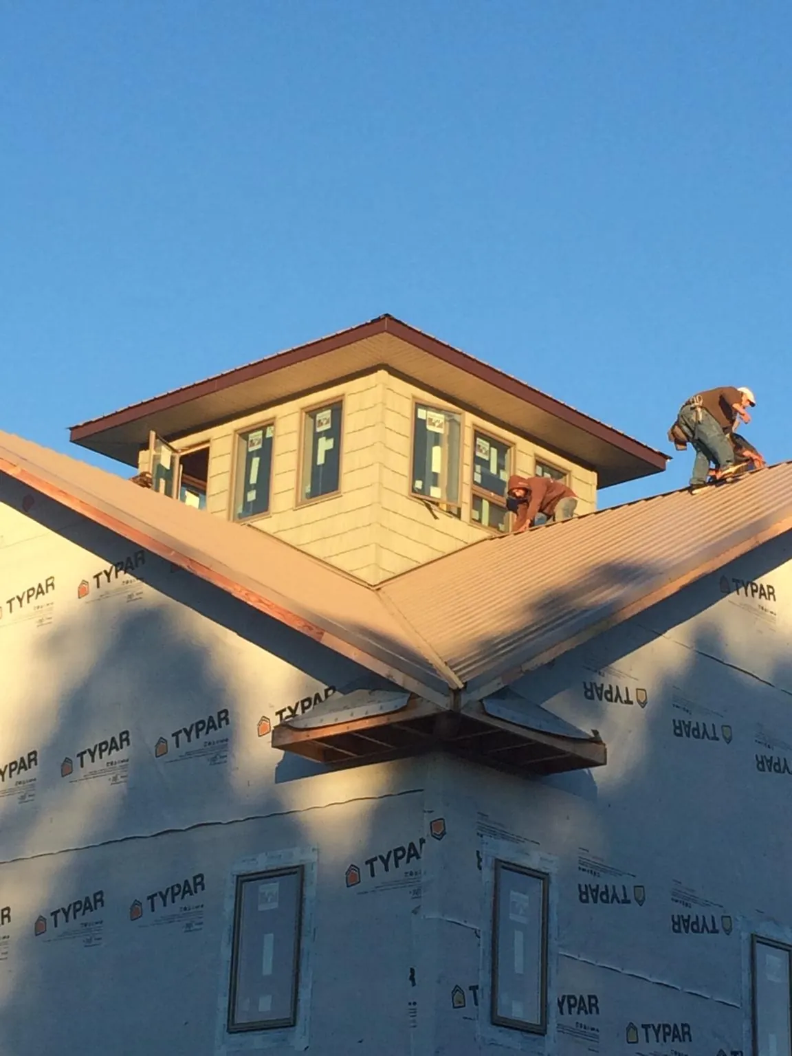 Roofers working around a rooftop cupola on a new metal roof at sunset — Roof Waterproofing in Mineral Wells by Roofing Brothers
